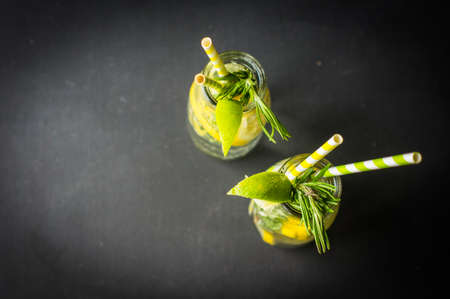 Fresh homemade detox lemonade with lime, lemon, rosemary, mint and ice on rustic wooden table with copyspaceの写真素材