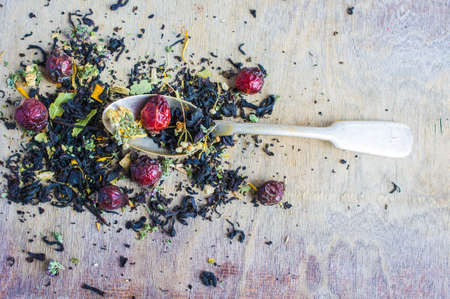 Dry tea leaves with flowersand fruits on wooden background with copyspace as a organic tea conceptの写真素材