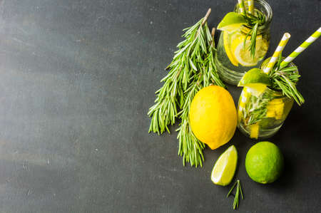 Fresh homemade detox lemonade with lime, lemon, rosemary, mint and ice on rustic wooden table with copyspaceの写真素材