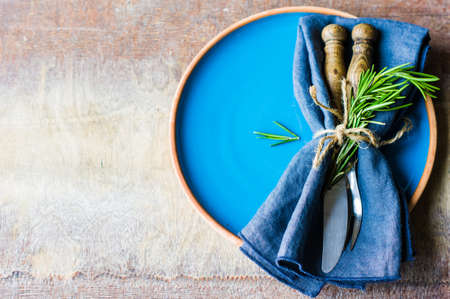 Rustic table setting with rosemary on dark wooden table with copyspaceの写真素材