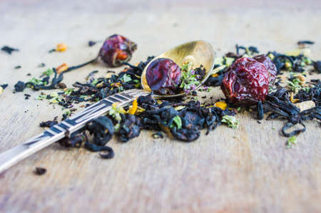 Dry tea leaves with flowersand fruits on wooden background with copyspace as a organic tea conceptの写真素材