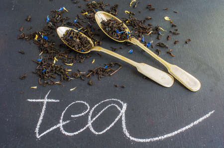 Dry tea leaves with flowersand fruits on wooden background with copyspace as a organic tea conceptの写真素材