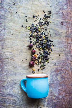 Dry tea leaves with flowersand fruits on wooden background with copyspace as a organic tea conceptの写真素材
