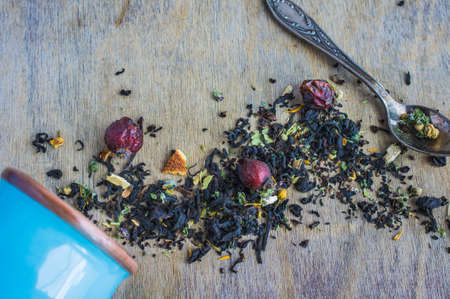 Dry tea leaves with flowersand fruits on wooden background with copyspace as a organic tea conceptの写真素材