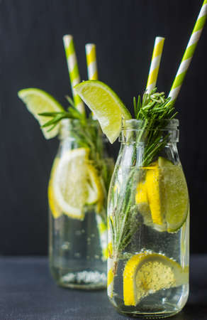 Fresh homemade detox lemonade with lime, lemon, rosemary, mint and ice on rustic wooden table with copyspaceの写真素材
