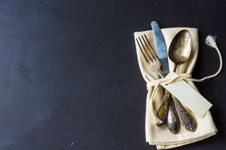 Rustic table setting - vintage silverware and cotton napkin  on dark background with copyspaceの写真素材
