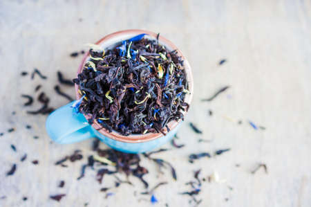 Dry tea leaves with flowersand fruits on wooden background with copyspace as a organic tea conceptの写真素材