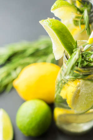 Fresh homemade detox lemonade with lime, lemon, rosemary, mint and ice on rustic wooden table with copyspaceの写真素材
