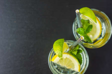 Fresh homemade detox lemonade with lime, lemon, rosemary, mint and ice on rustic wooden table with copyspaceの写真素材