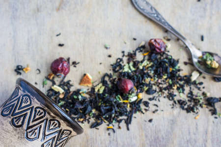 Dry tea leaves with flowersand fruits on wooden background with copyspace as a organic tea conceptの写真素材