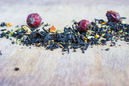 Dry tea leaves with flowersand fruits on wooden background with copyspace as a organic tea conceptの写真素材