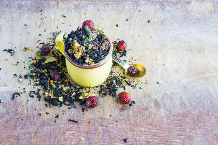 Dry tea leaves with flowersand fruits on wooden background with copyspace as a organic tea concept
