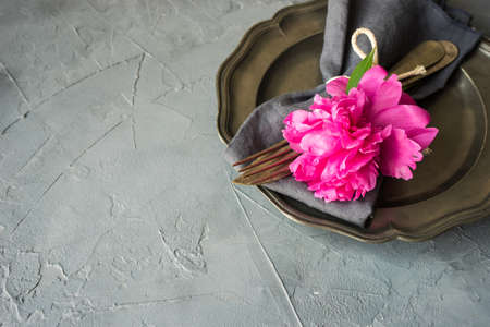 Summer table setting with bright peonies on dark rustic table with copyspaceの写真素材
