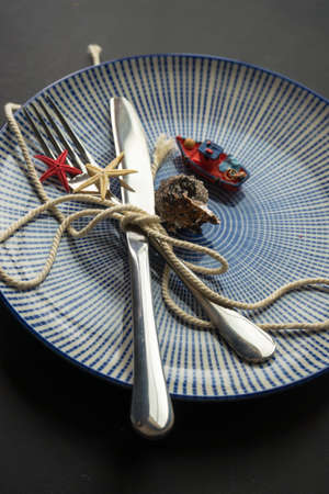 Summer vacation marine table setting with rustic plates and silverware on wooden background with copyspaceの写真素材