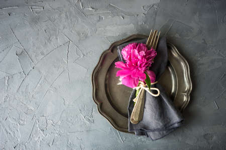 Summer table setting with bright peonies on dark rustic table with copyspaceの写真素材