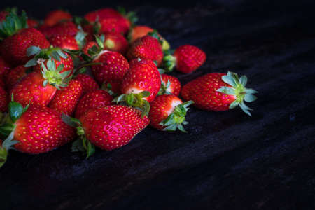 Organic strawberry in a rustic plate on dark chalkboard with ice and mintの写真素材