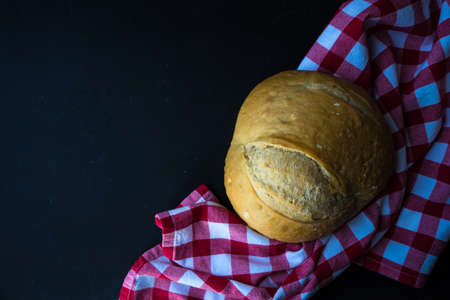 Freshbaked homemade bread on a towel on dark wooden tableの写真素材