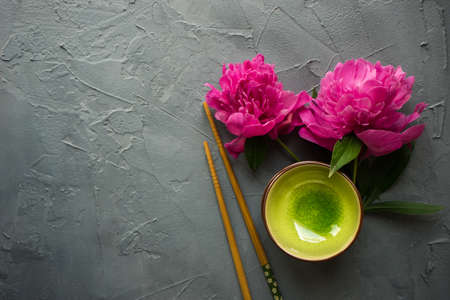 Summer table setting for dinner with asian dishes with bright peonies on dark rustic table with copyspaceの写真素材