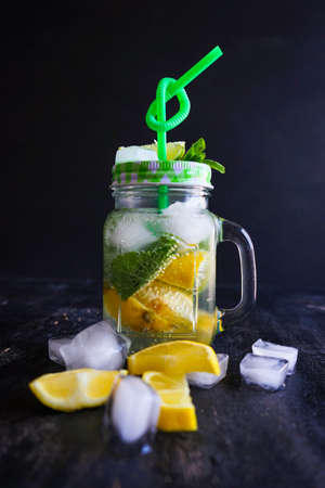 Organic food concept with bottle of healthy drink with lime, lemon and mint and water on rustic wooden table with copyspaceの写真素材