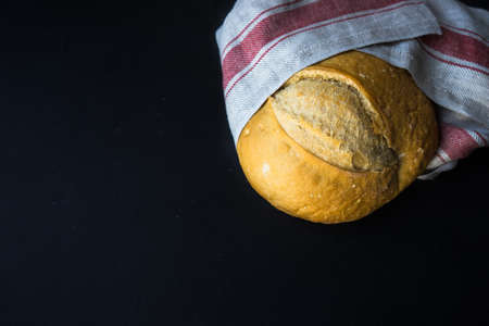 Freshbaked homemade bread on a towel on dark wooden table