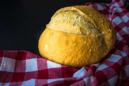 Freshbaked homemade bread on a towel on dark wooden tableの写真素材