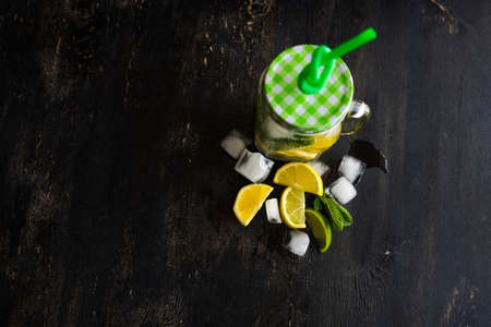 Organic food concept with bottle of healthy drink with lime, lemon and mint and water on rustic wooden table with copyspaceの写真素材