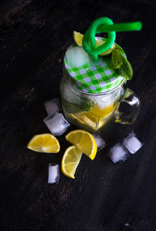 Organic food concept with bottle of healthy drink with lime, lemon and mint and water on rustic wooden table with copyspaceの写真素材