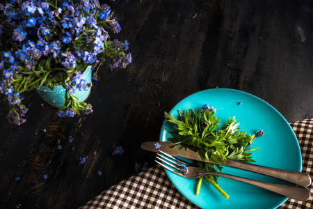 Summer floral table setting with bright blue forget-me-not flowers on wooden tableの写真素材