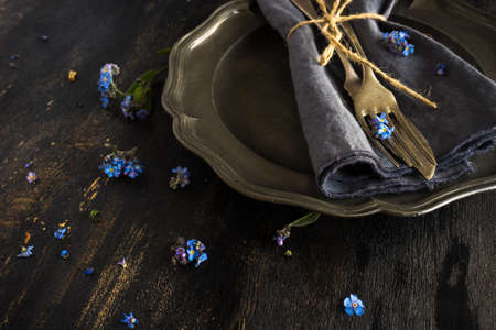 Summer floral table setting with bright blue forget-me-not flowers on wooden table