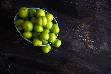 Green cherry plum on dark wooden tableの写真素材