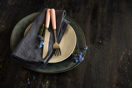 Summer floral table setting with bright blue forget-me-not flowers on wooden tableの写真素材