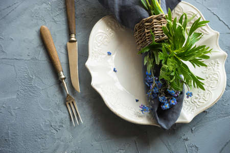 Summer floral table setting with bright blue forget-me-not flowers on wooden table