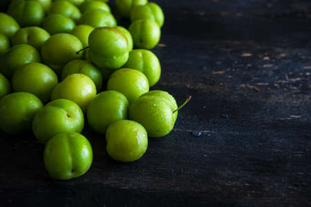 Green cherry plum on dark wooden tableの写真素材