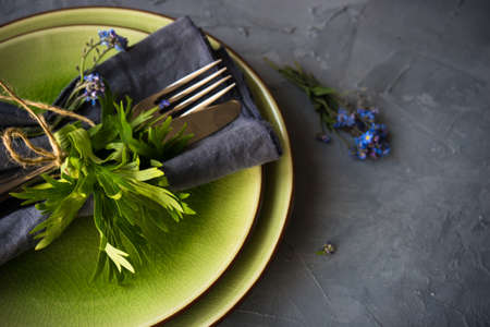 Summer floral table setting with bright blue forget-me-not flowers on wooden table