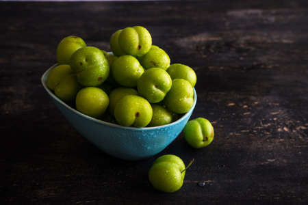 Green cherry plum on dark wooden tableの写真素材