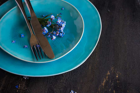 Summer floral table setting with bright blue forget-me-not flowers on wooden tableの写真素材