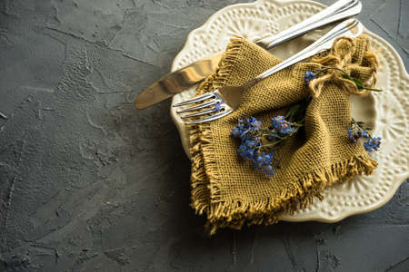 Summer floral table setting with bright blue forget-me-not flowers on wooden tableの写真素材