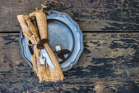 Autumnal table setting with acorns and rustic plates on dark wooden table