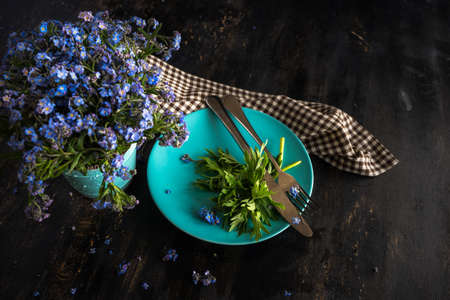 Summer floral table setting with bright blue forget-me-not flowers on wooden tableの写真素材