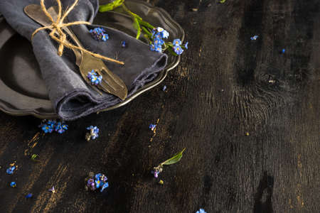 Summer floral table setting with bright blue forget-me-not flowers on wooden tableの写真素材