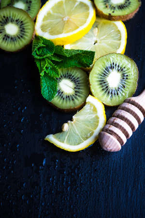 Flat lay with kiwi, lemon and mint on stone background with copyspaceの写真素材