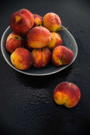 Organic ripe peach fruits on dark wooden backgroundの写真素材