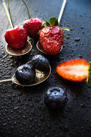 Summer fruits on spoons on wooden background with copyspace