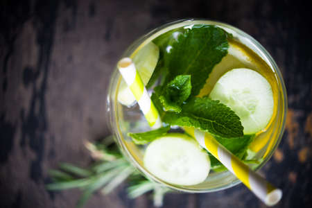 Detox drink with cucumber, lemon, mint and rosemary on dark wooden backgroundの写真素材