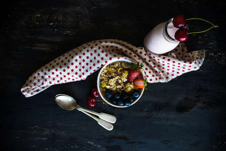 Healthy breakfast with oatmeals and organic berries - blueberry and strawberry on dark wooden table...