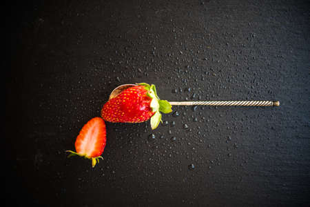 Ripe strawberry on vintage metal spoon on dark background with copyspaceの写真素材