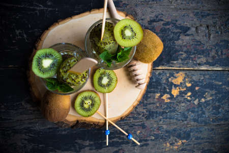 Summer fruit dessert - kiwi lollipops with mint and ice on rustic plate on concrete backgroundの写真素材