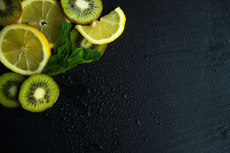 Flat lay with kiwi, lemon and mint on stone background with copyspaceの写真素材