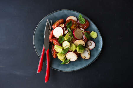 Spring healthy salald with fresh organic tomatoes, radish and rukkola herb on rustic plate with napkin and silverwareの写真素材