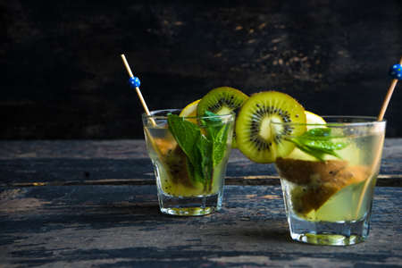 Organic food concept of fresh kiwi smoothie on grey concrete background with fruits and mintの写真素材